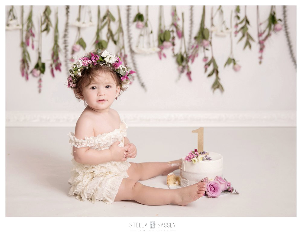 One year old in studio during cake smash with a flower backdrop