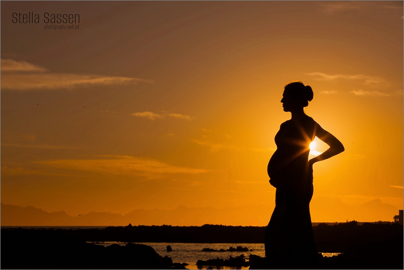 Silhouette of pregnant woman on beach during maternity shoot