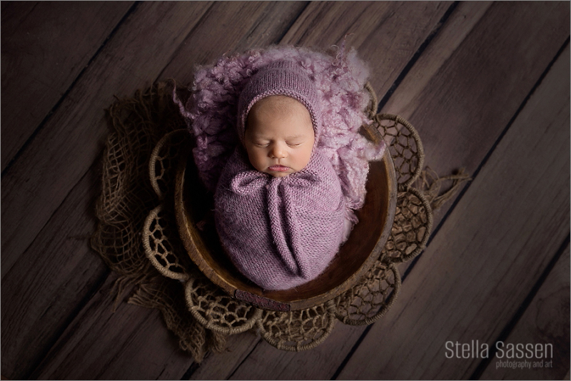 Newborn baby wrapped and wearing bonnet sleeping in basket