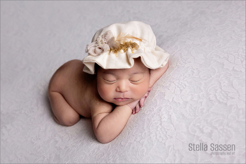 newborn baby with flowery hat lying on lace sleeping during photo shoot in cape town