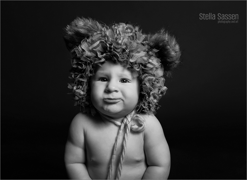 Sitting baby with adorable expression wearing a bear hat
