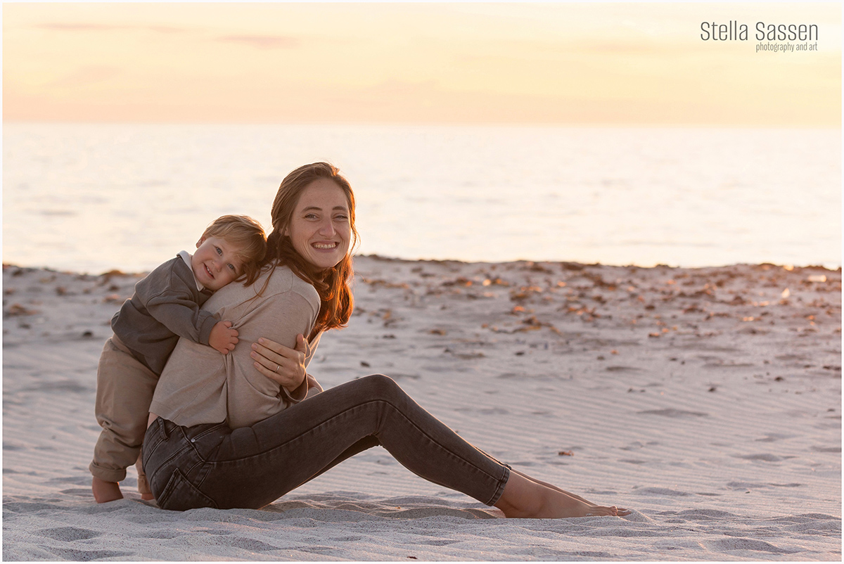 young boy hugging mom on beach during family photo shoot